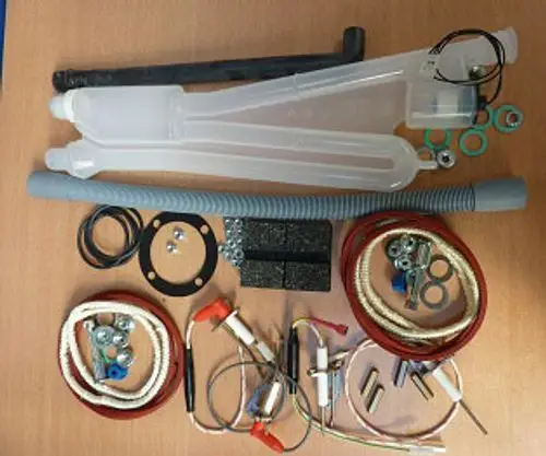 Wartungssatz mit verschiedenen Komponenten, darunter Rohre, Dichtungen und Kabel, übersichtlich auf einem Tisch angeordnet, zur Verwendung in Remeha Heizsystemen.